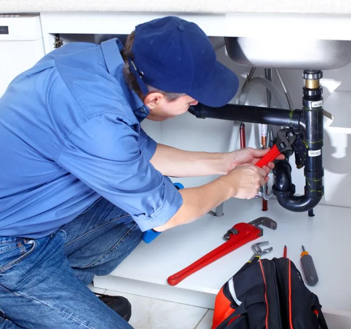 A professional plumber working on the under sink pipes with his handy tools